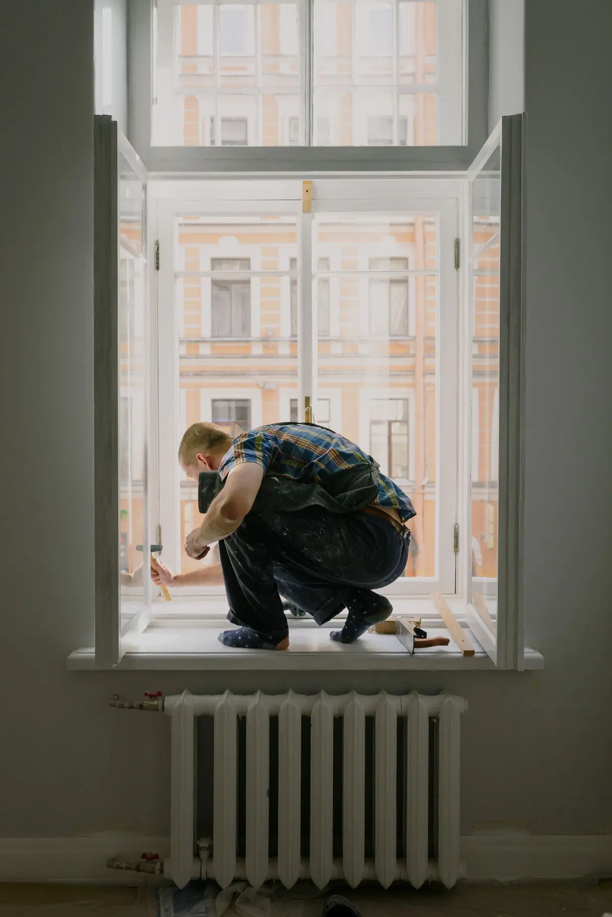 Hausmeister bei einer Reparatur am Fenster eines Wohnhauses